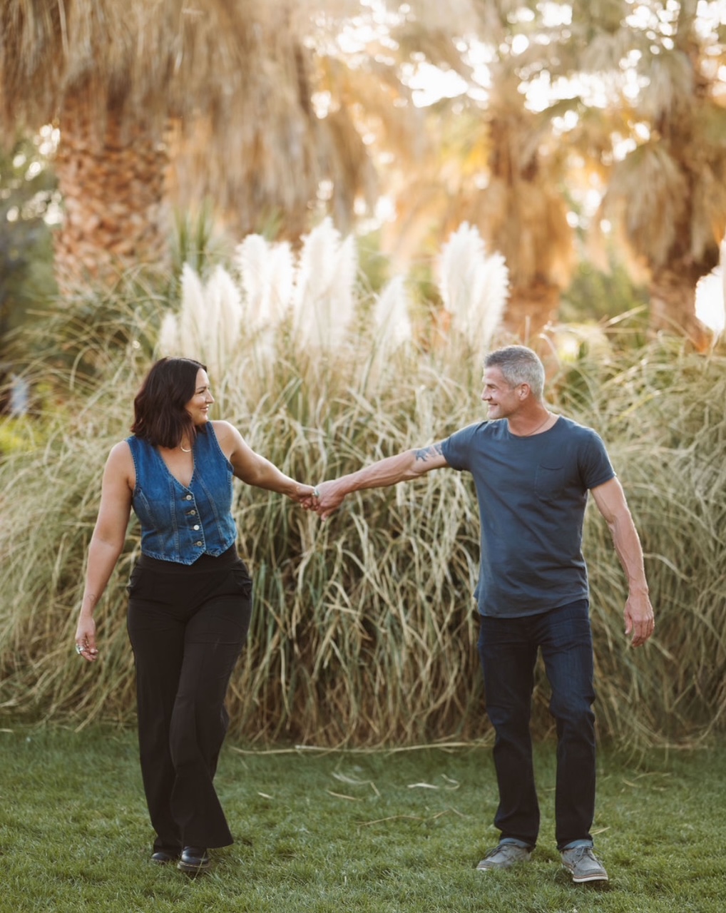Couple holding hands walking together in golden sunlight