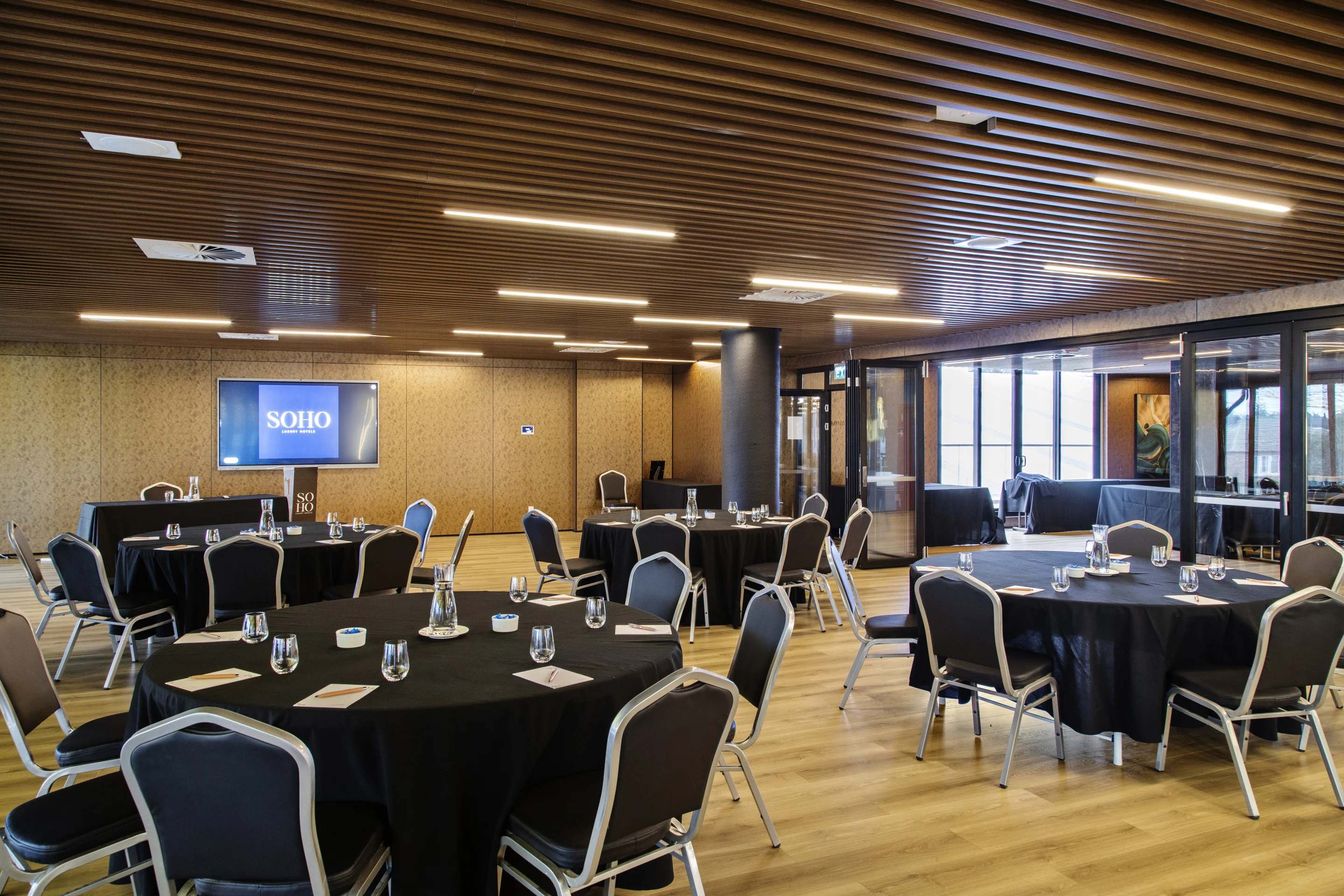 SOHO Hotel conference room with round tables and modern wooden ceiling